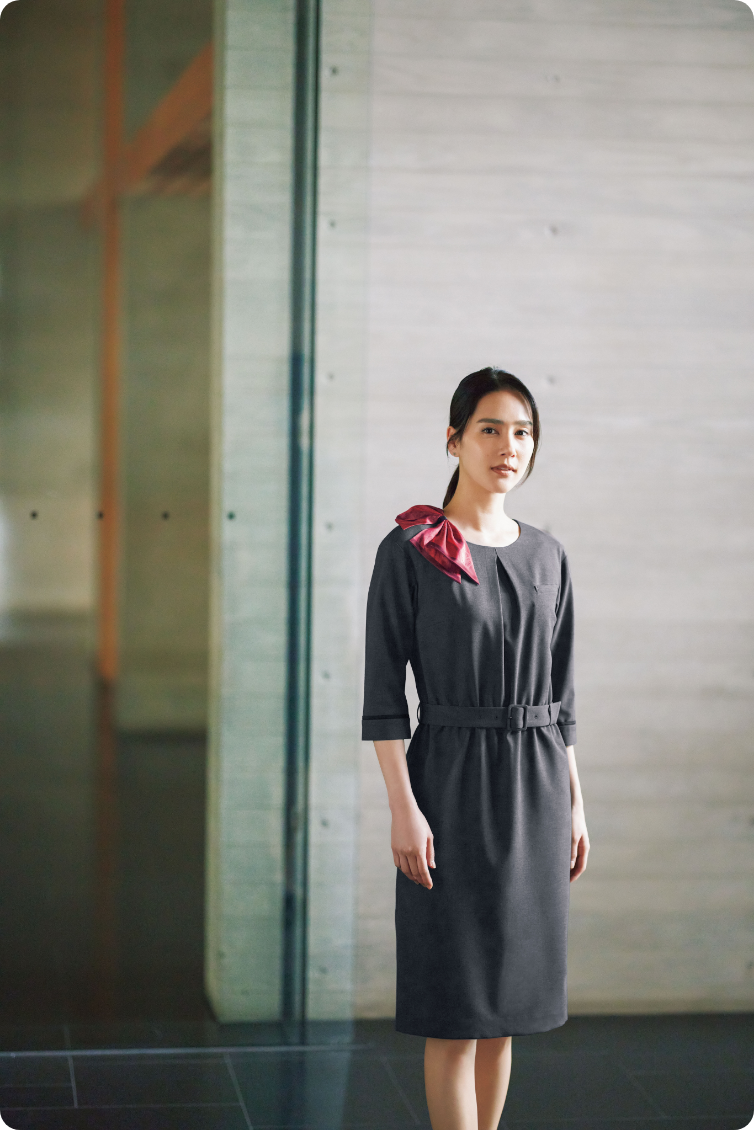 ENJOY Noirのグレー色の制服を着用し、廊下で立つホテルスタッフ