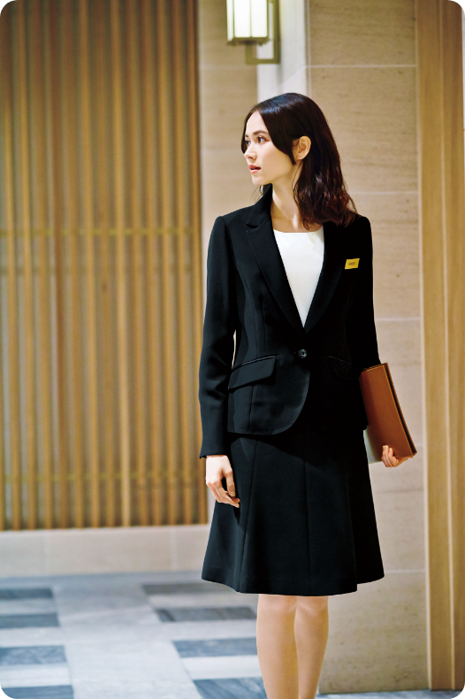 ENJOY Noirの黒色の制服を着用し、ファイルを持っているレセプションスタッフ