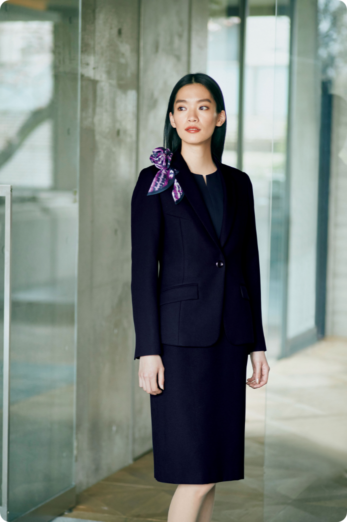 ENJOY Noirの黒色の制服を着用し、歩いているレセプションスタッフ